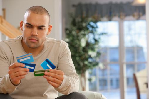 Young Man holding 4 Credit Cards